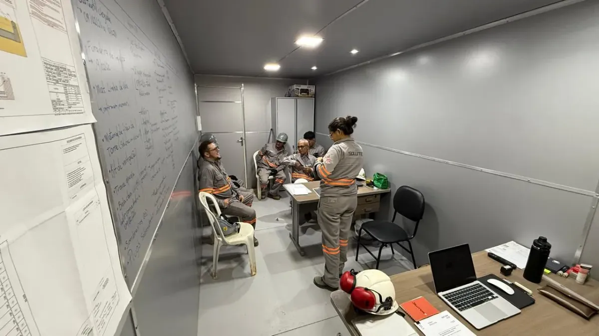 Equipe da Solutec AM em reunião de alinhamento no escritório de canteiro, com quadro de planejamento e documentos técnicos